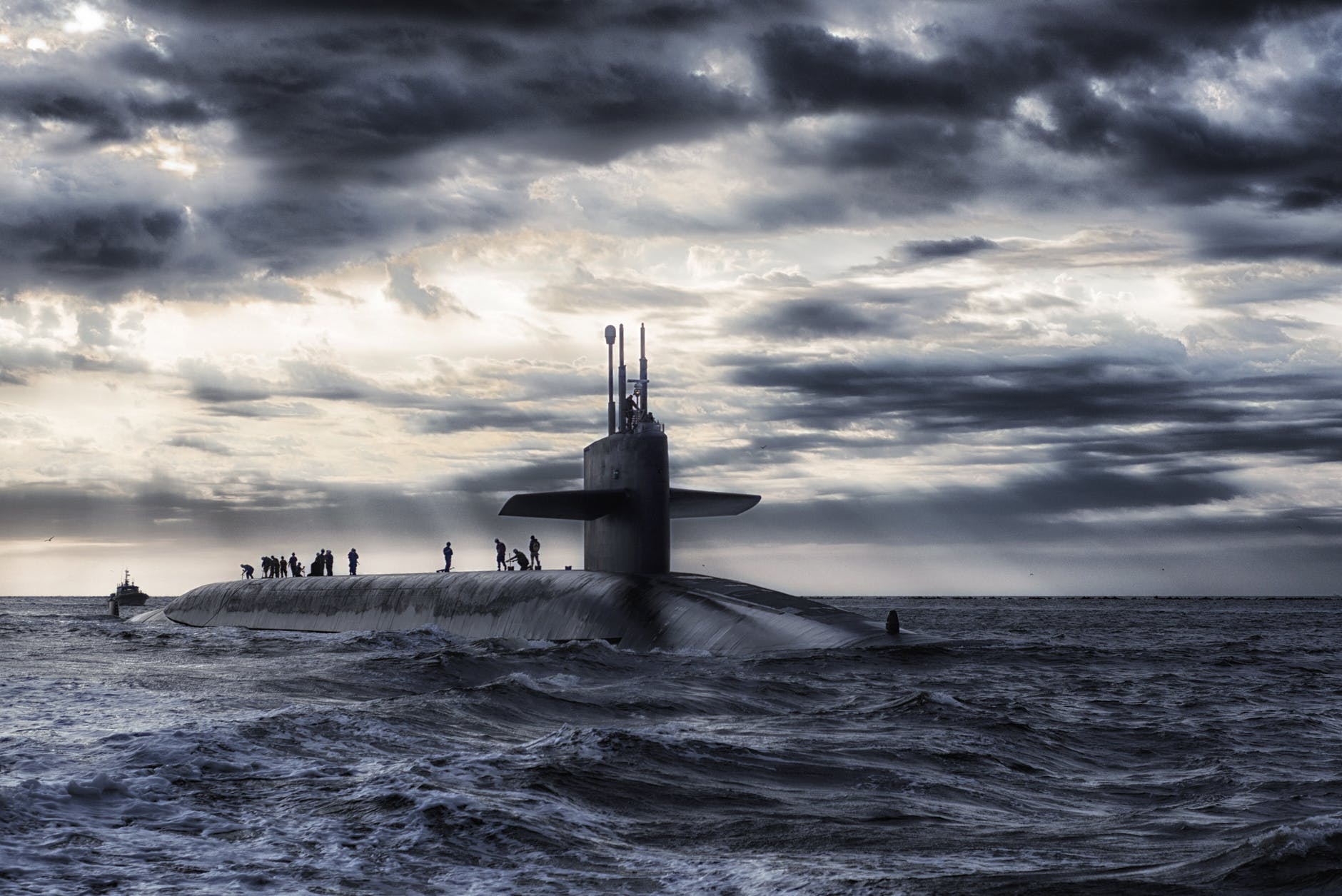 grey submarine in body of water under cloudy sky