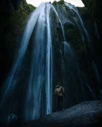 photo of man standing near the waterfalls